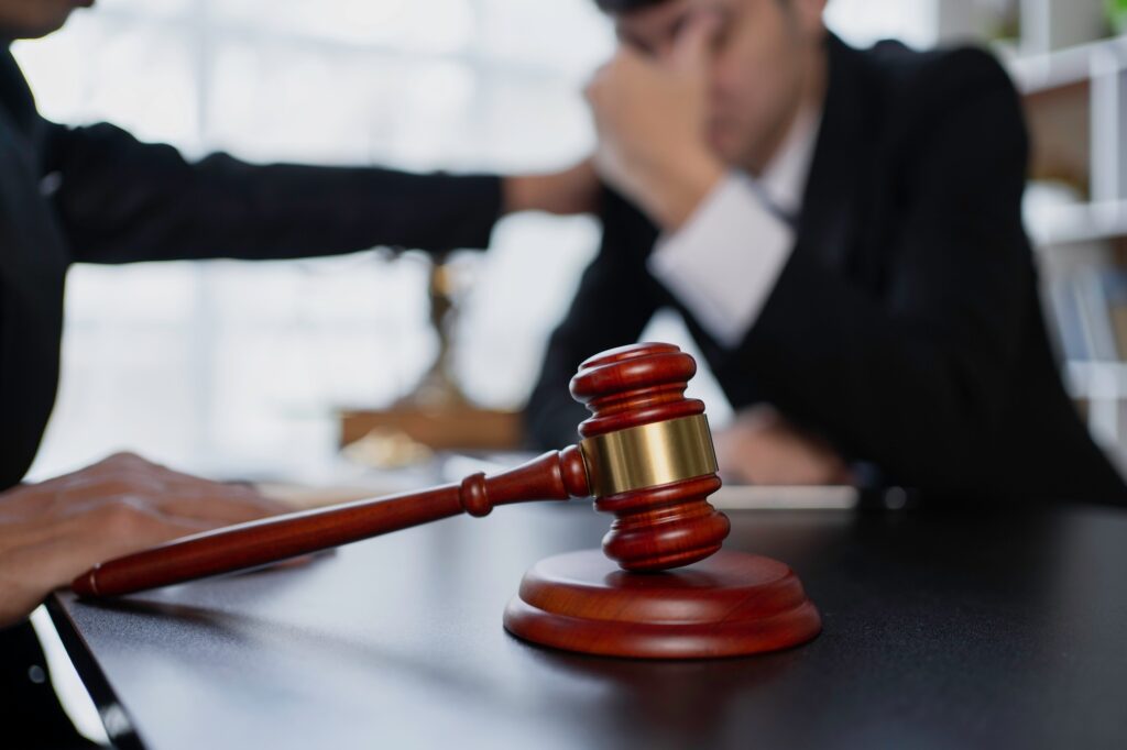 Close-up of a gavel with two people discussing legal matters in a courtroom or office